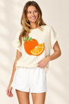 Studio view of cream short-sleeve orange citrus sweater